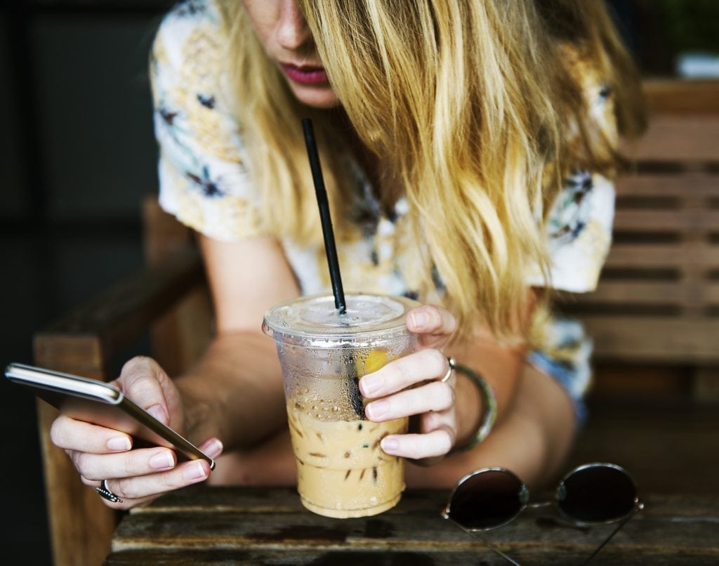 A college student drinks an iced latte whilst surfing online